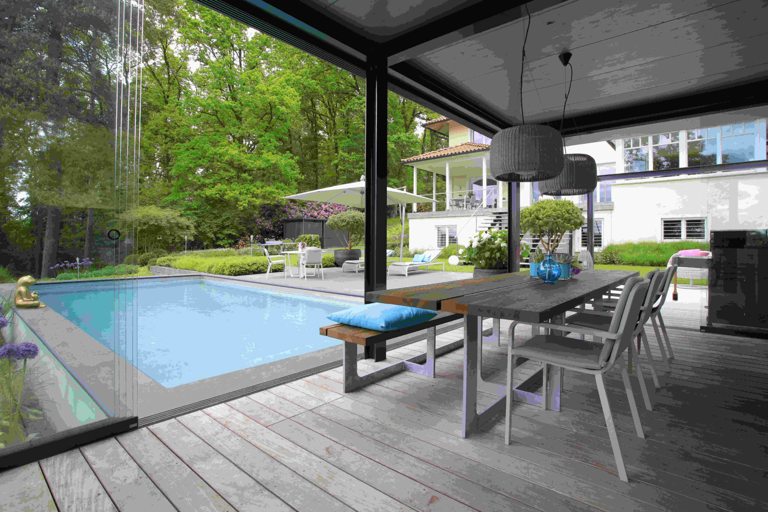 Moderne Terrasse mit Pool und Essbereich Terrasse mit einem Essbereich und einem Pool, umgeben von Pflanzen und Bäumen.