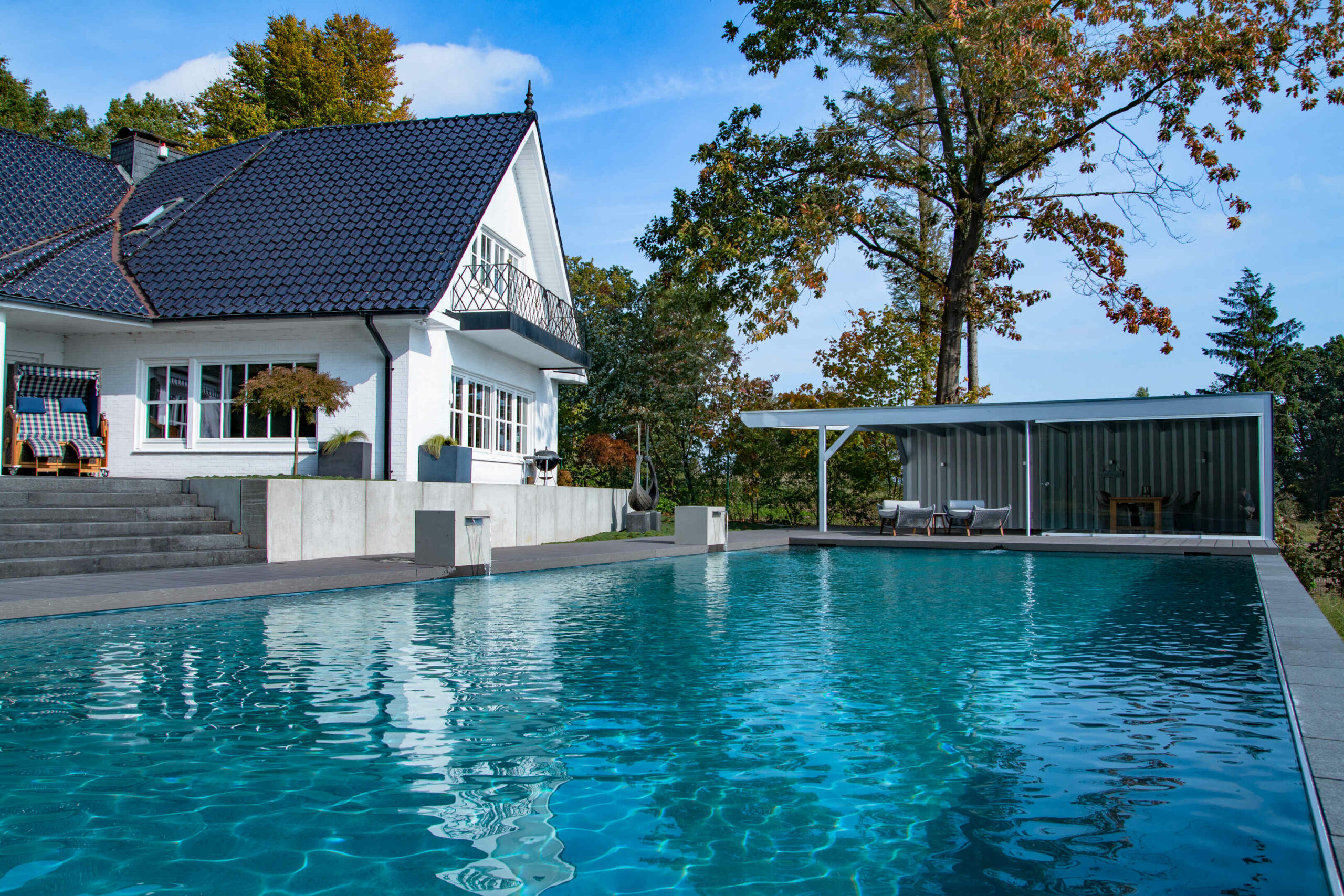 Haus mit Pool und Gartenlandschaft Ein modernes Haus mit einem großen Pool und einer gepflegten Gartenlandschaft im Hintergrund.