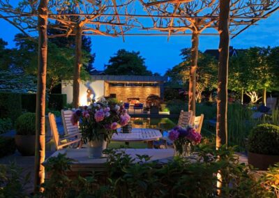 Gartenbeleuchtung bei Nacht mit einem Tisch und Stühlen sowie Blumenarrangements.