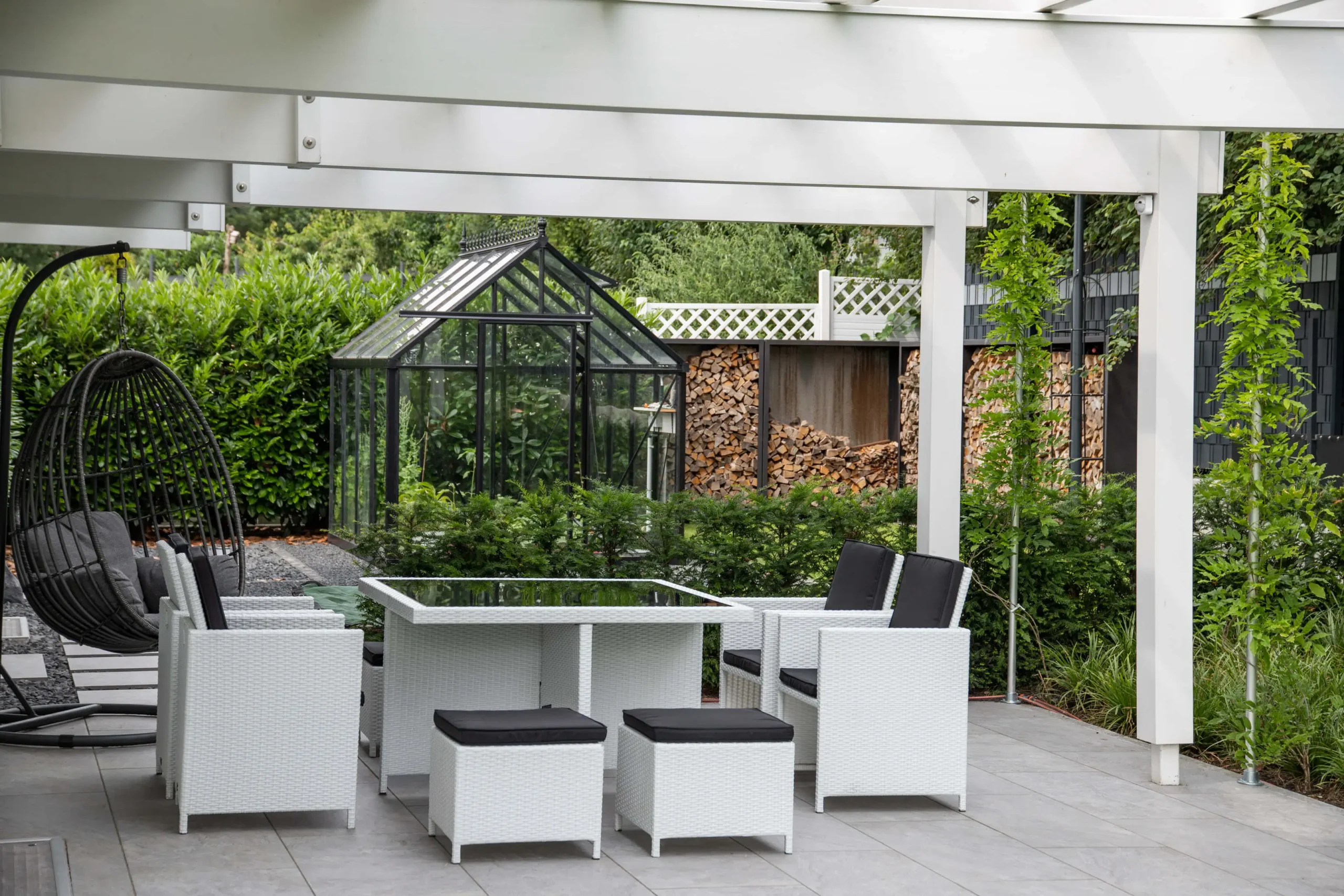 Moderne Architektur eines Hauses mit großen Fenstern und einem Garten, umgeben von Bäumen und einer gepflegten Rasenfläche.